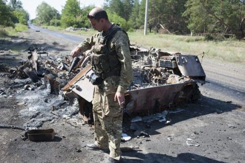 Lính Ukraine bên xác của một xe bọc thép do trúng đạn tên lửa vác vai của quân ly khai