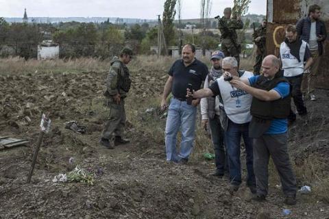 Các chuyên gia OSCE chụp ảnh những ngôi mộ tập thể ở khu vực thuộc quyền kiểm soát của quân chính phủ