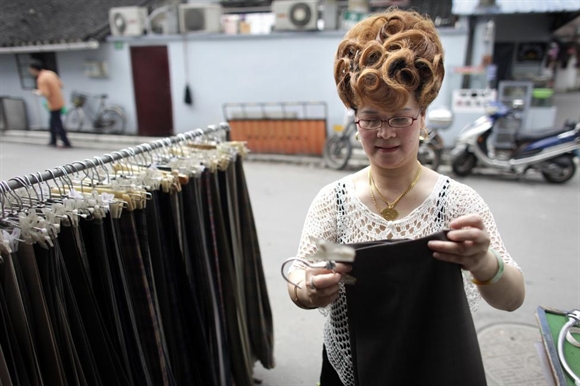 Bà chủ cửa hàng Gong Chui Zhen sắp xếp quần áo bên ngoài cửa hiệu tại Thượng Hải. 