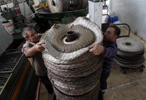 Công nhân đưa bột ô-liu nhão vào máy ép trước khi chiết dầu tại thị trấn Anqoun, phía Nam Lebanon.