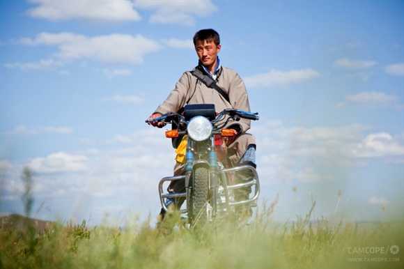Cưỡi mô-tô trên thảo nguyên. Nhiều người Mông Cổ giờ đây có thể mua xe gắn máy của Trung Quốc. Và cùng với ngựa, xe gắn máy trở thành phương tiện đi lại khá phổ biến. 