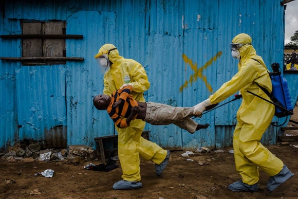 Nhân viên y tế di chuyển cậu bé 8 tuổi James Dorbor nhiễm Ebola tại Monrovia, Liberia hôm 5/9. Dù được chuyển tới trung tâm điều trị Ebola nhưng Dorbor tử vong vài ngày sau đó. Ảnh: NYtimes