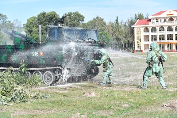 Sau khi tiếp cận mục tiêu, các chiến sĩ nhanh chóng gỡ ngụy trang; sử dụng súng phun bàn chải, súng phun vòi rồng thực hành tiêu tẩy vũ khí, trang bị. Sau khi tiếp cận mục tiêu, các chiến sĩ nhanh chóng gỡ ngụy trang; sử dụng súng phun bàn chải, súng phun vòi rồng thực hành tiêu tẩy vũ khí, trang bị.